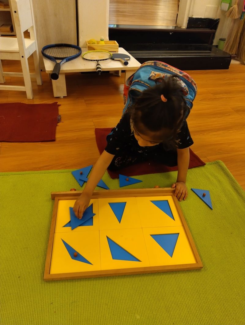 A child's hands at work with Montessori constructive-triangle materials in Flourish's prepared environment